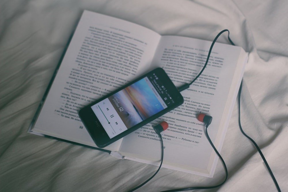 Celular con adifonos encima de un libro.