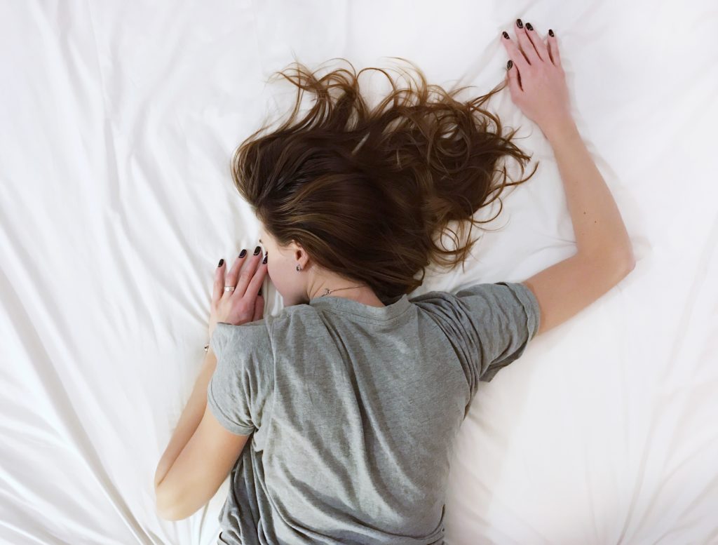 Mujer durmiendo en una cama con sabanas blancas, 